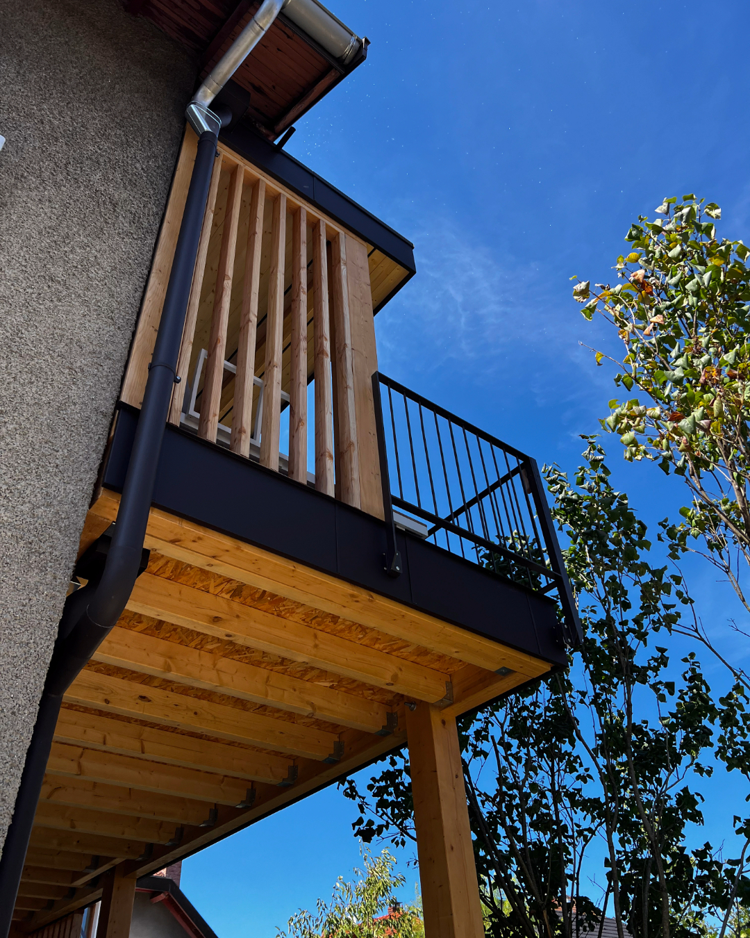 Structure en bois réalisée par Alpine Habitat, mettant en avant leur expertise en charpente, avec une vue en contre-plongée de la construction.